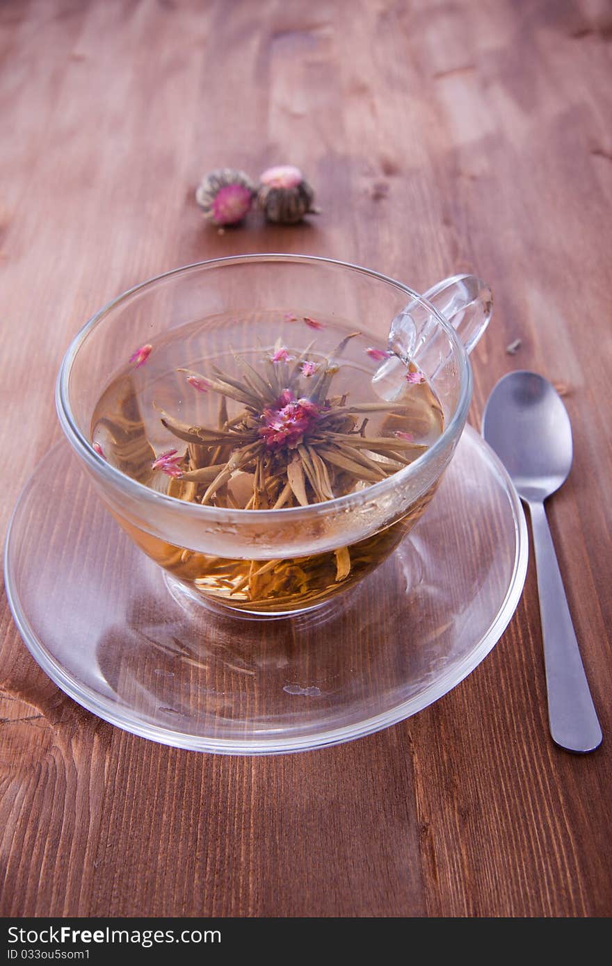 Transparent cup of a green tea with the teaspoon on the wooden table. Transparent cup of a green tea with the teaspoon on the wooden table