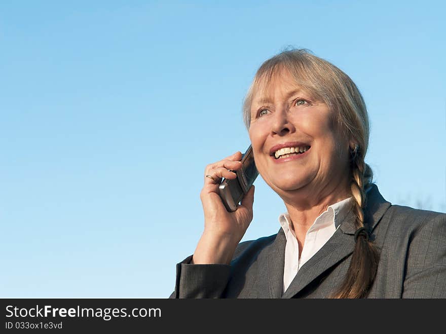 Happy mature businesswoman using cellphone.