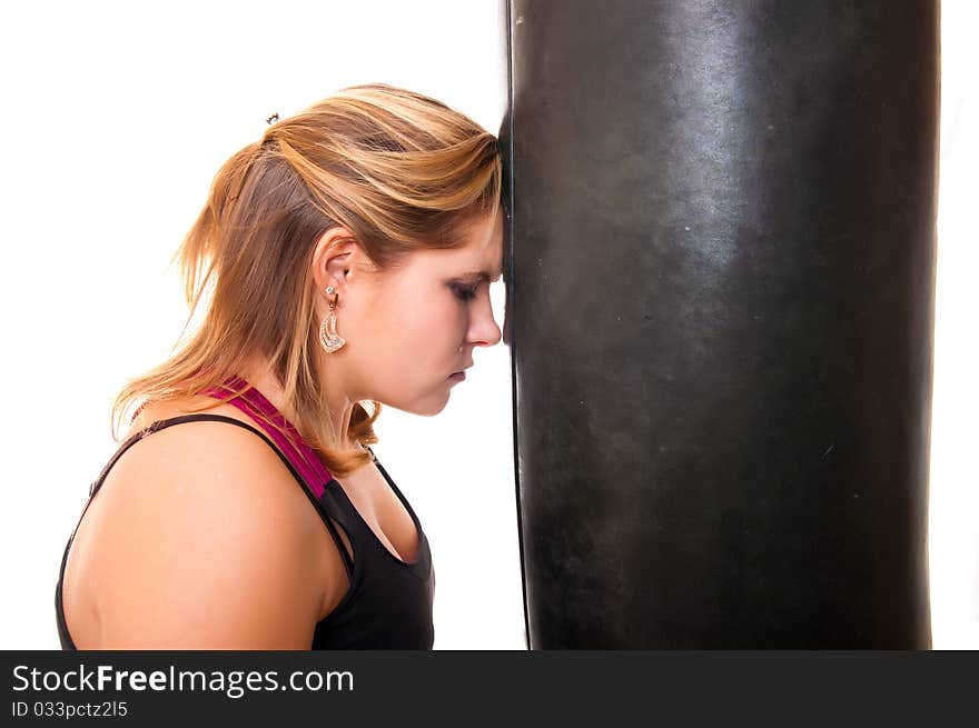 A tired woman rests on a boxer bag. A tired woman rests on a boxer bag