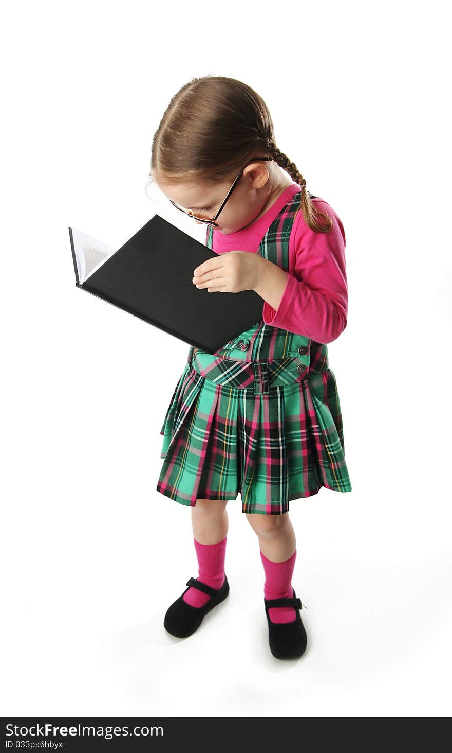 Cute preschool age girl wearing eyeglasses reading from a heavy book. Cute preschool age girl wearing eyeglasses reading from a heavy book