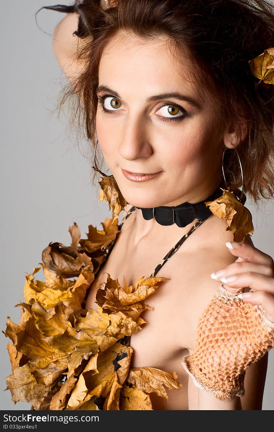 Portrait of beautiful, young girl in lingerie made of leaves. Gray background. Studio shot. Portrait of beautiful, young girl in lingerie made of leaves. Gray background. Studio shot.