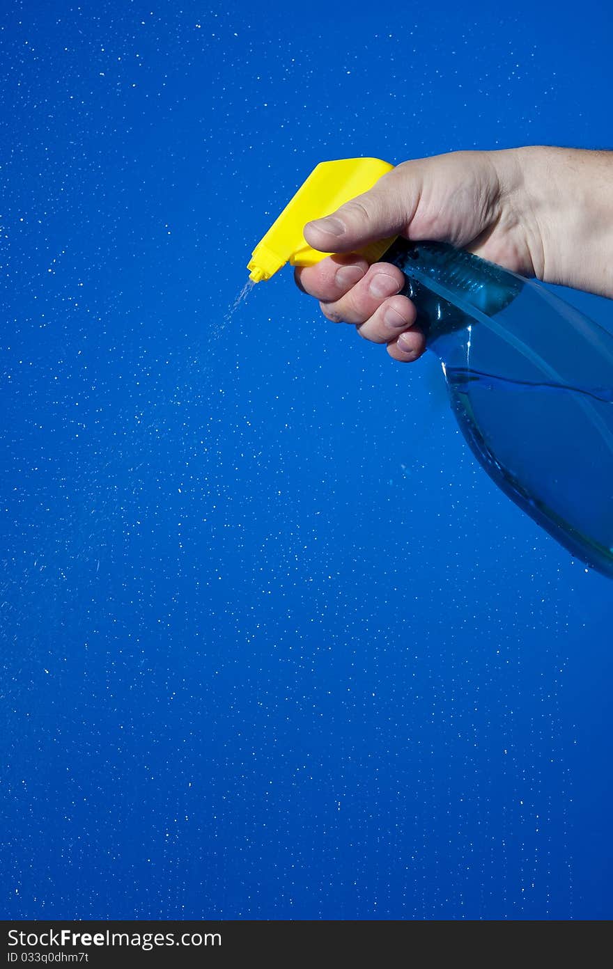 Hahd holding bottle of cleaning solution on the blue background