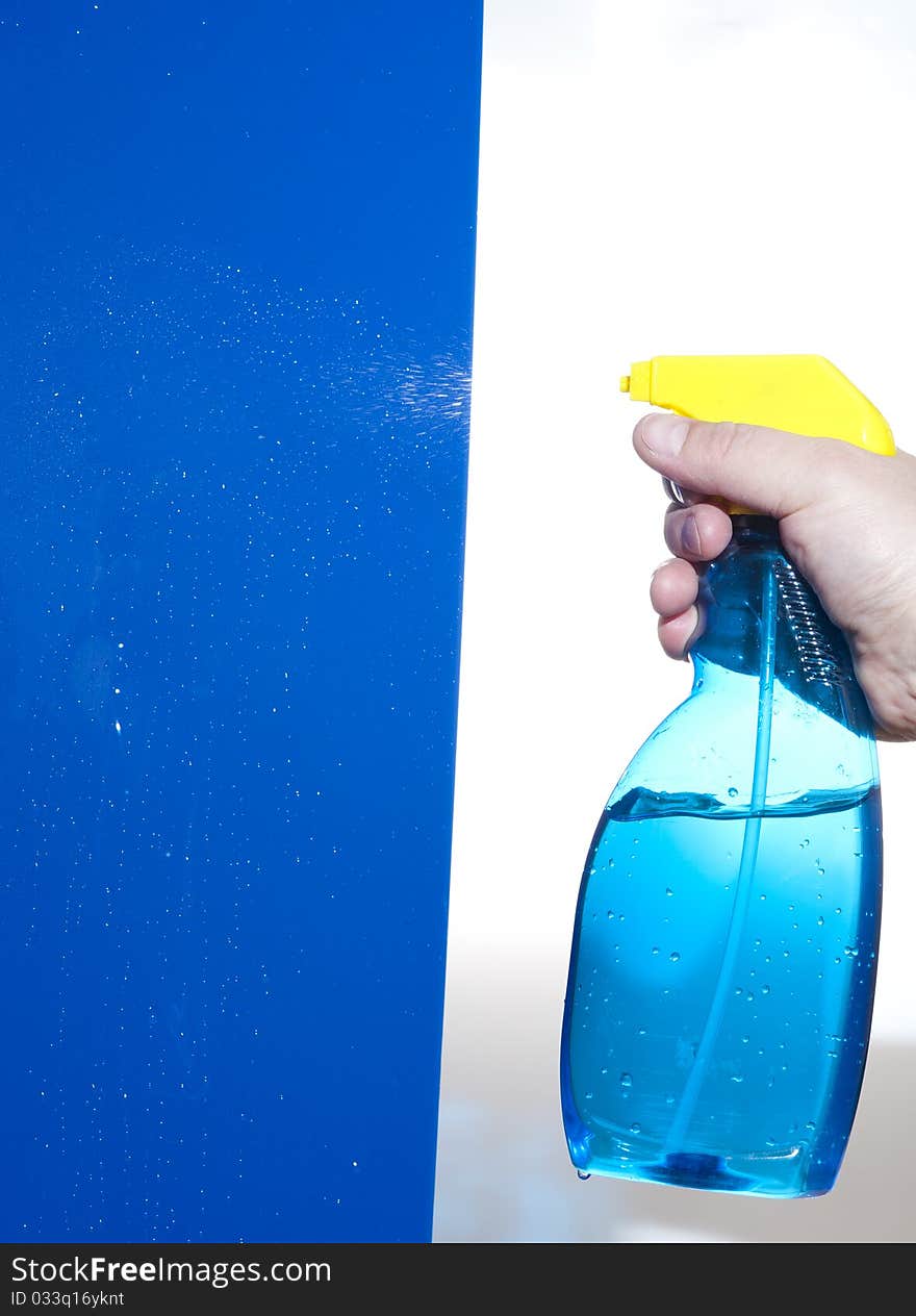 Hahd holding bottle of cleaning solution on the blue background