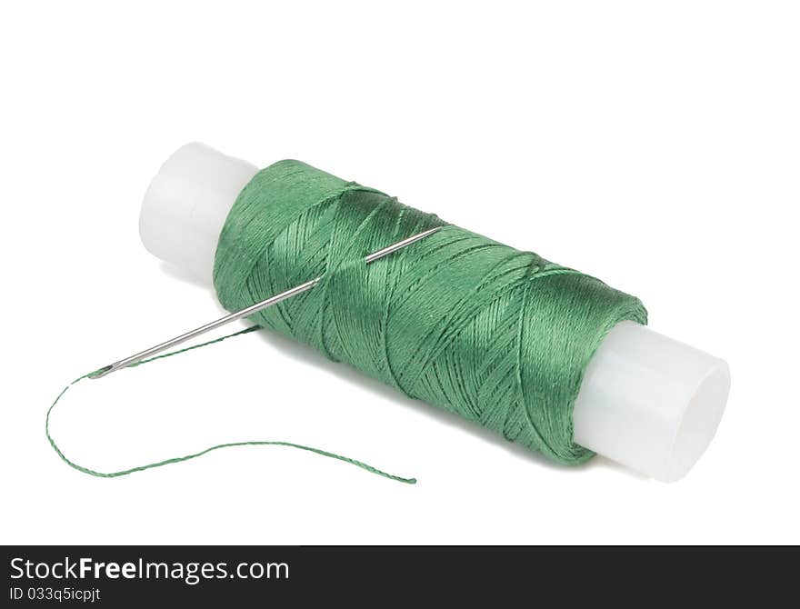 Green spool with needle on a white background