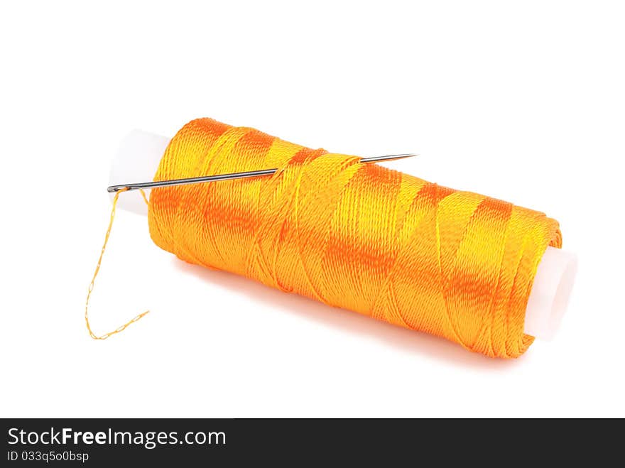 Orange spool with needle on a white background