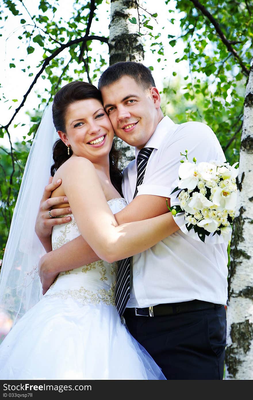 Happy bride and groom at the birches in the park