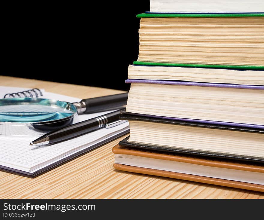 Pile of book and pen on notebook on black background