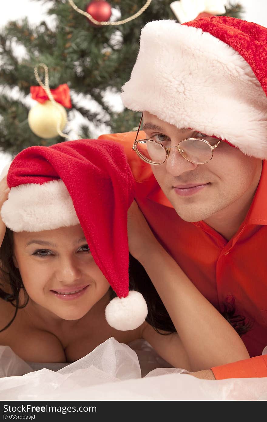 Young lovely couple near a Christmas tree. Isolated over white background