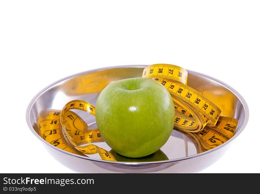 An apple with measure tape in a chrome bowl isolated over white