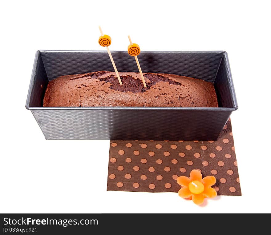 Home baked chocolate cake in a cake pan isolated over white