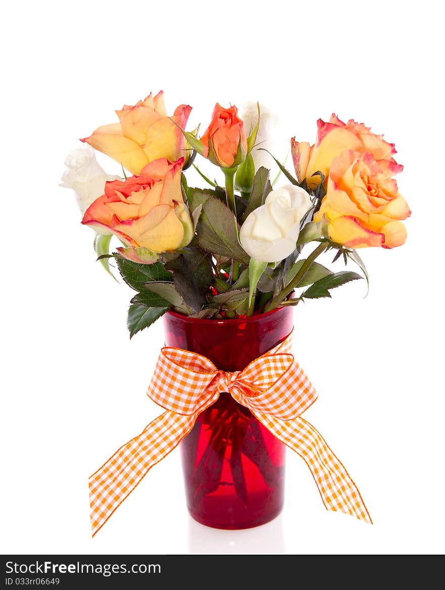 Orange and white roses in a red glass vase isolated over white