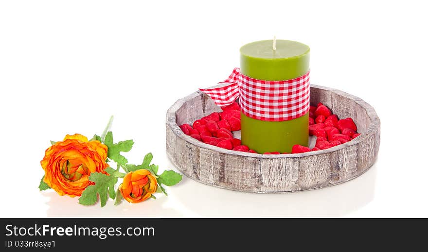 A wooden tray with a green candle decorated with stones and flowers isolated over white. A wooden tray with a green candle decorated with stones and flowers isolated over white