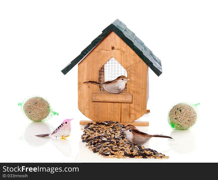 A birdhouse with birds and seeds isolated over white