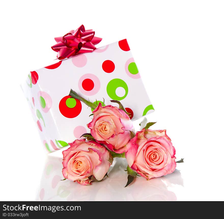 A cheerful gift on top of three pink orange roses isolated over white. A cheerful gift on top of three pink orange roses isolated over white