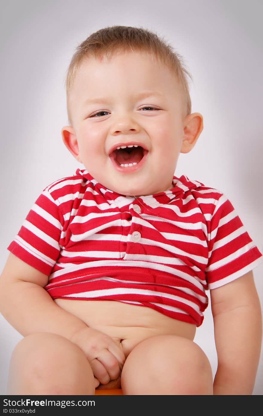 A boy sits on a gray background