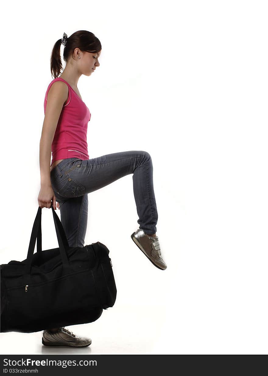 Slim girl striding with a big black sports bag. Motion blur is slightly present. Studio shot against white background. Slim girl striding with a big black sports bag. Motion blur is slightly present. Studio shot against white background