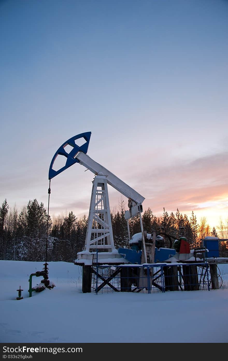 Oil pump on the sunset sky background. Oil pump on the sunset sky background