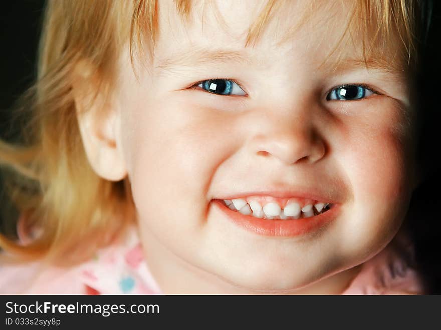 Portrait of the pretty smiling little girl with blue eyes close-up