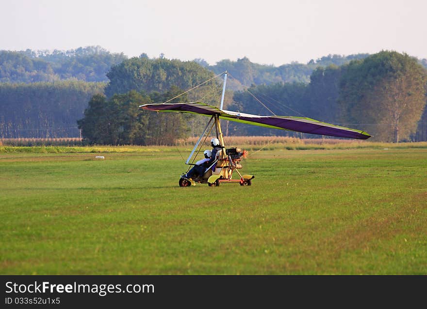 Hang glider is landing in a grain field