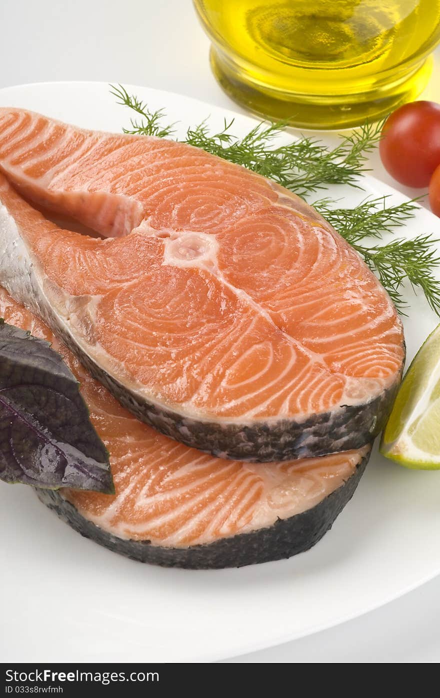 Raw salmon steak with herbs and vegetables close-up