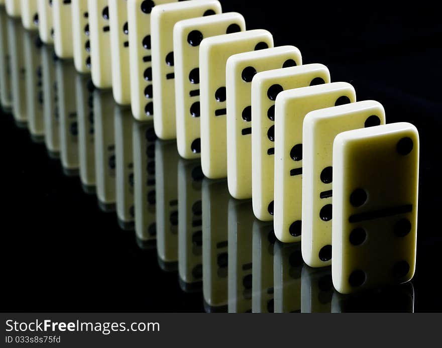 Dominoes waiting to fall, white tiles on black background. Dominoes waiting to fall, white tiles on black background.