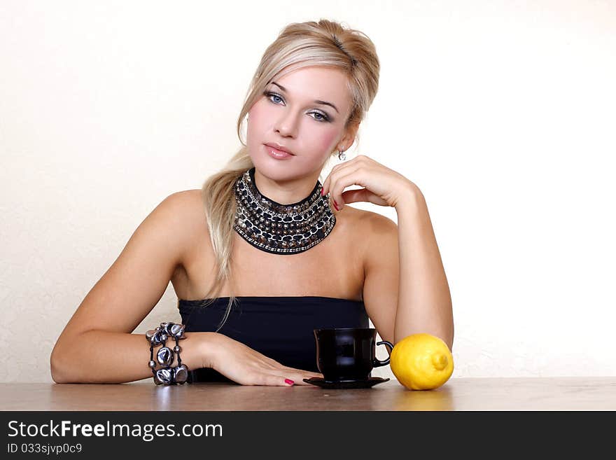 Woman with cup of hot drink with lemon against yellow wall at home