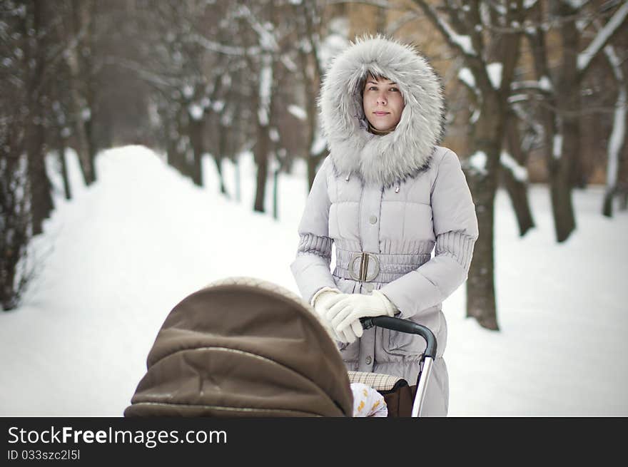 Woman with stroller in a winter park. Woman with stroller in a winter park