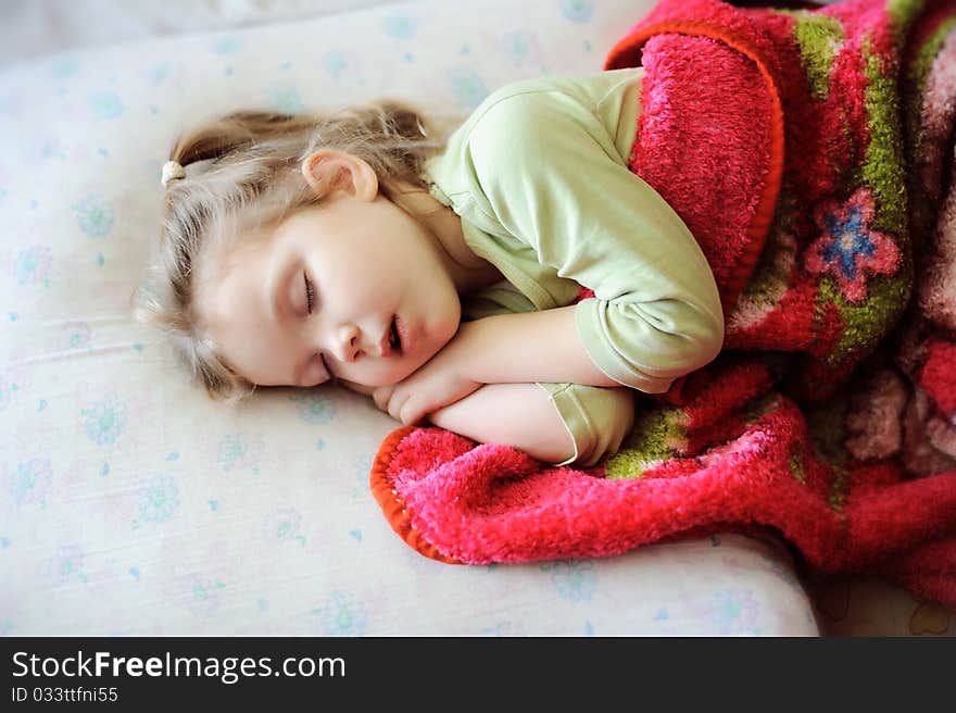An image of a little girl sleeping on a bad. An image of a little girl sleeping on a bad