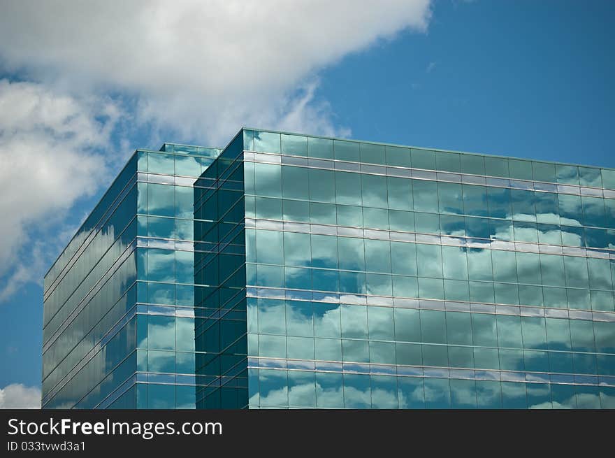 Deep blue sky and clouds are reflected in the shiny windows of this modern office building. Deep blue sky and clouds are reflected in the shiny windows of this modern office building.