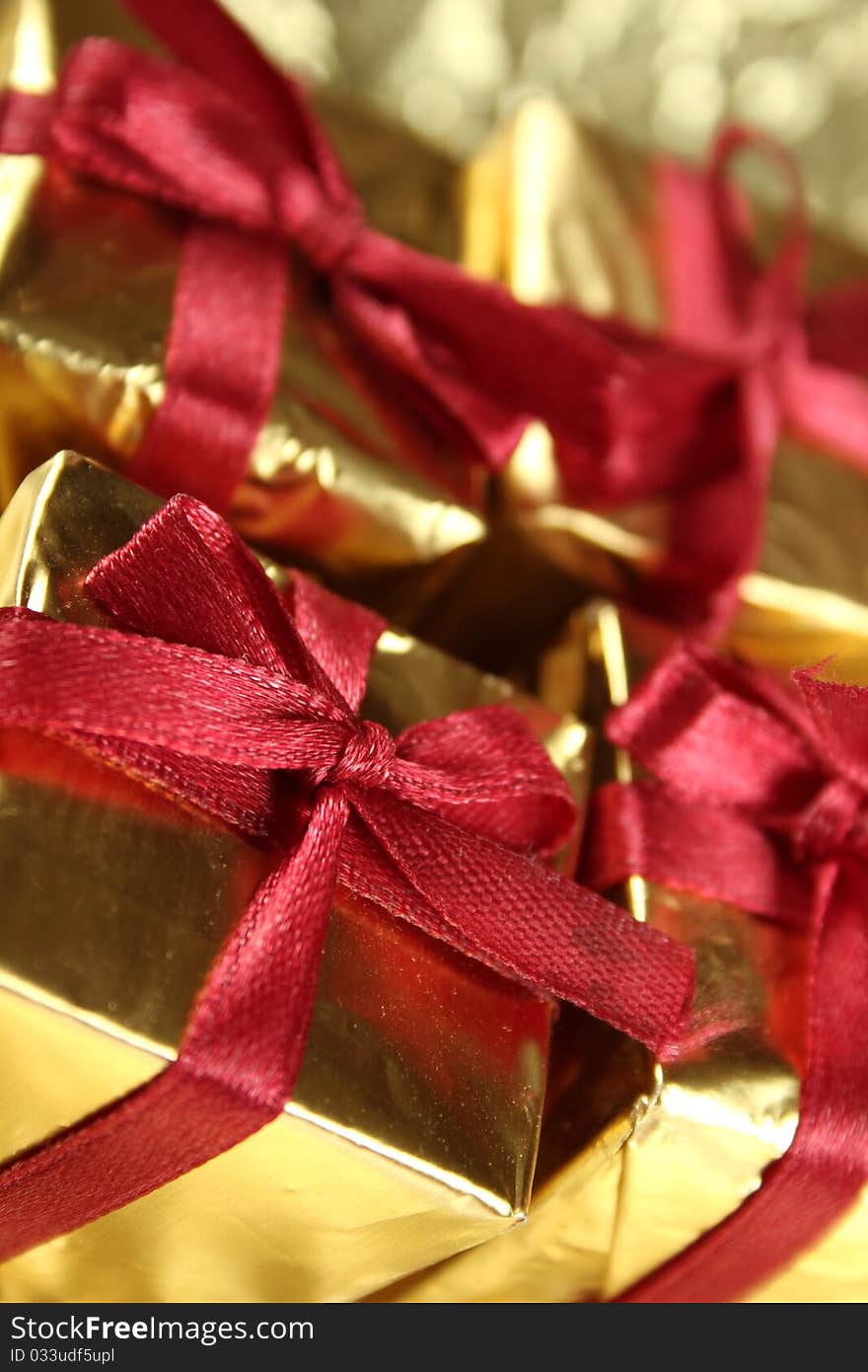 On a gold background four gold gift boxes with red ribbons. On a gold background four gold gift boxes with red ribbons