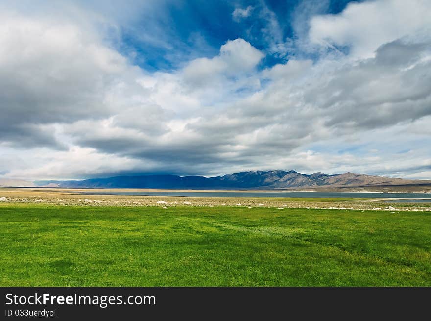 Green field the blue sky white clouds mountains. Green field the blue sky white clouds mountains