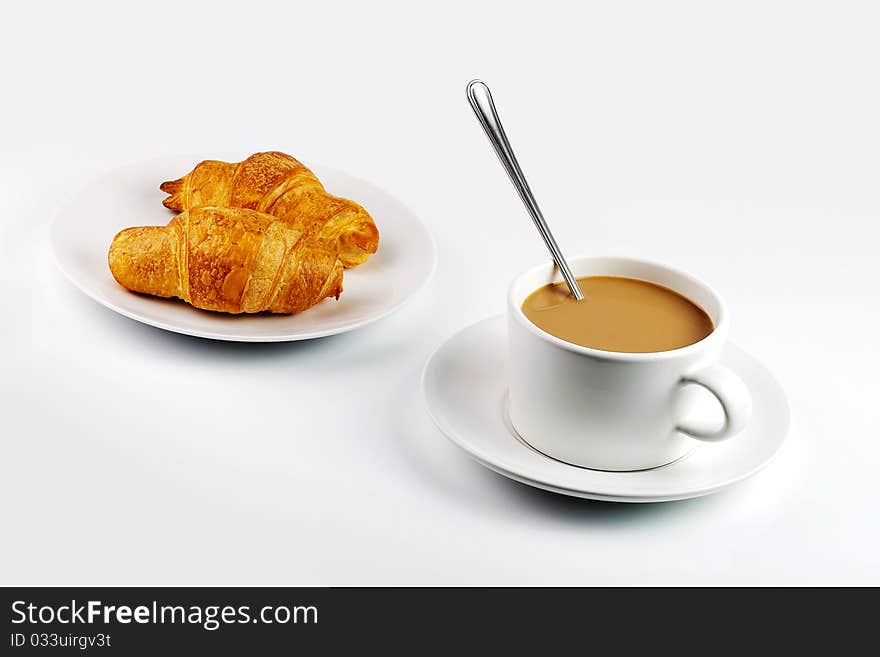 White coffee mug and croissants on plate