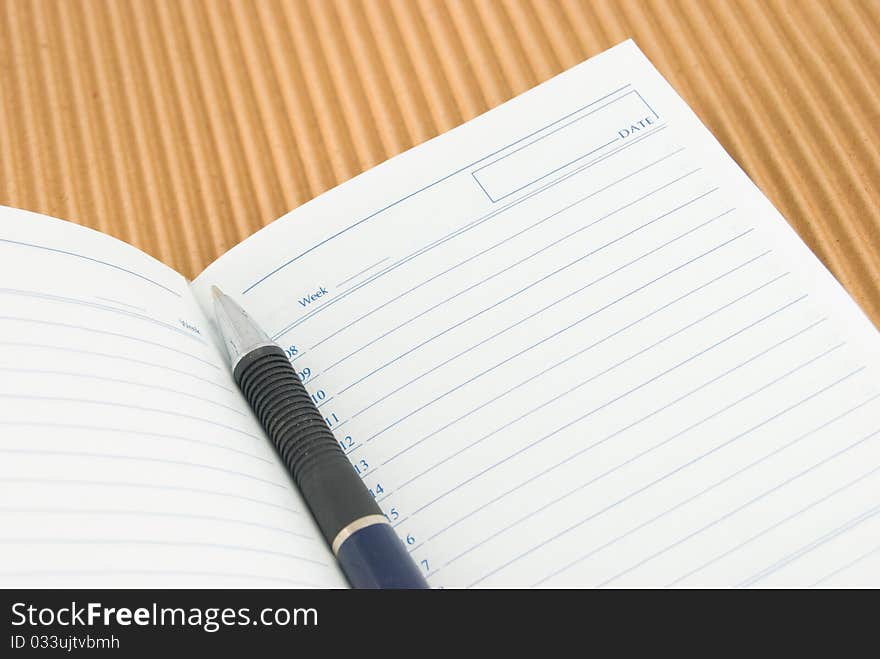 The opened notebook and pen on a cardboard background