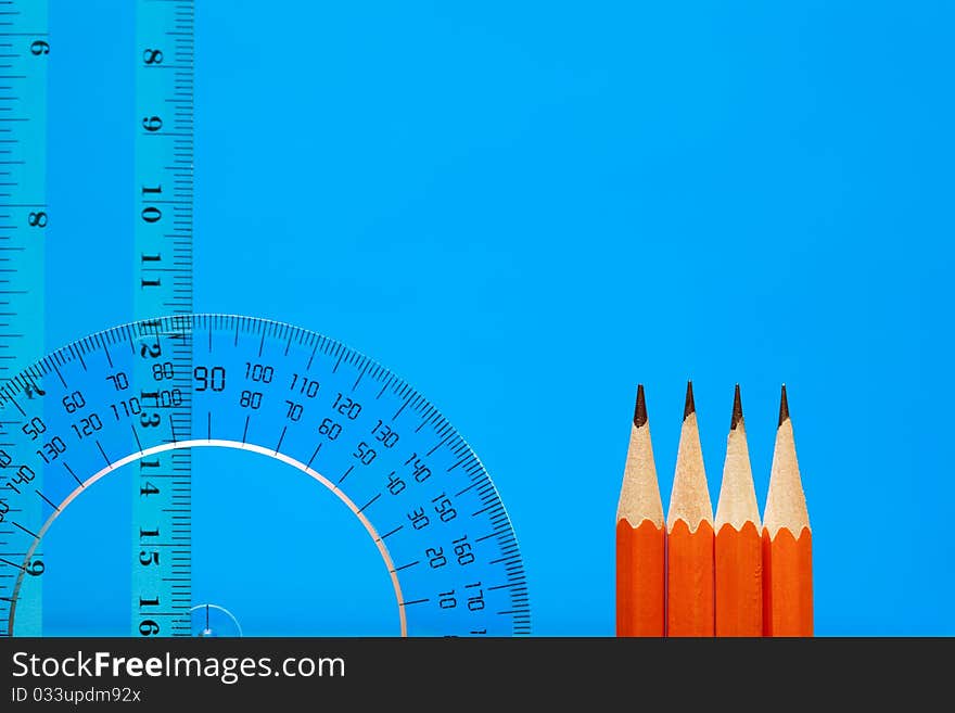 Transparent plastic protractor and ruler near pencils on blue background with copy space. Transparent plastic protractor and ruler near pencils on blue background with copy space