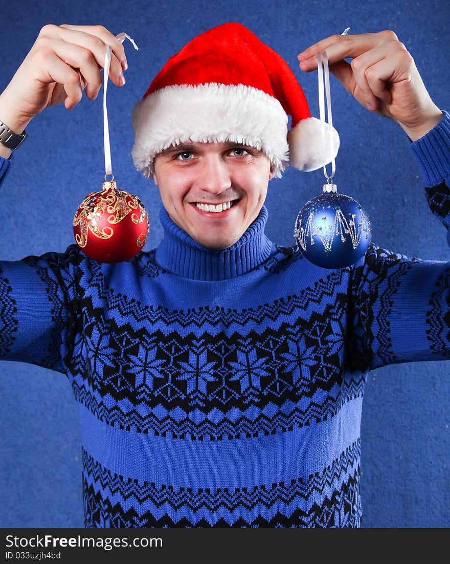 Man in blue sweater and red chrismas hat at blue background. Man in blue sweater and red chrismas hat at blue background