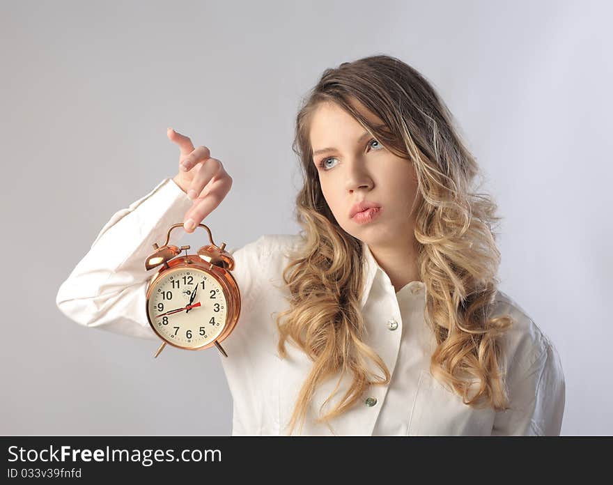 Bored woman holding an alarm clock. Bored woman holding an alarm clock