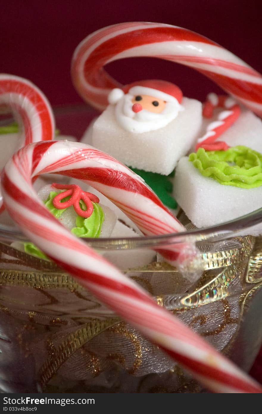 Chirstmas sugar cubes in a glass bowl with candy canes. Chirstmas sugar cubes in a glass bowl with candy canes.