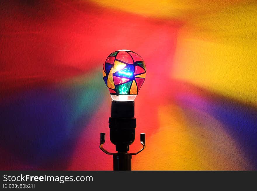 A colorful lightbulb with painted rainbow colors projecting onto the wall behind it with copyspace with room for your text. A colorful lightbulb with painted rainbow colors projecting onto the wall behind it with copyspace with room for your text