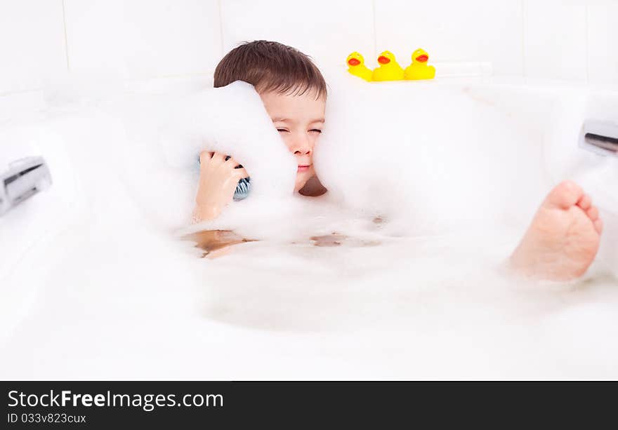 Cute four year old boy taking a relaxing bath with foam. Cute four year old boy taking a relaxing bath with foam