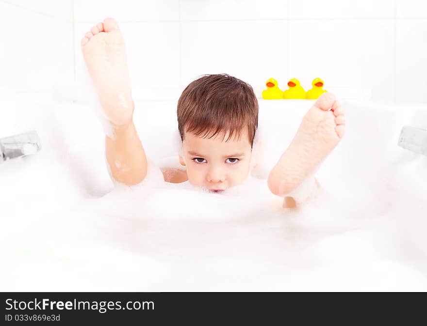 Cute four year old boy taking a relaxing bath with foam. Cute four year old boy taking a relaxing bath with foam