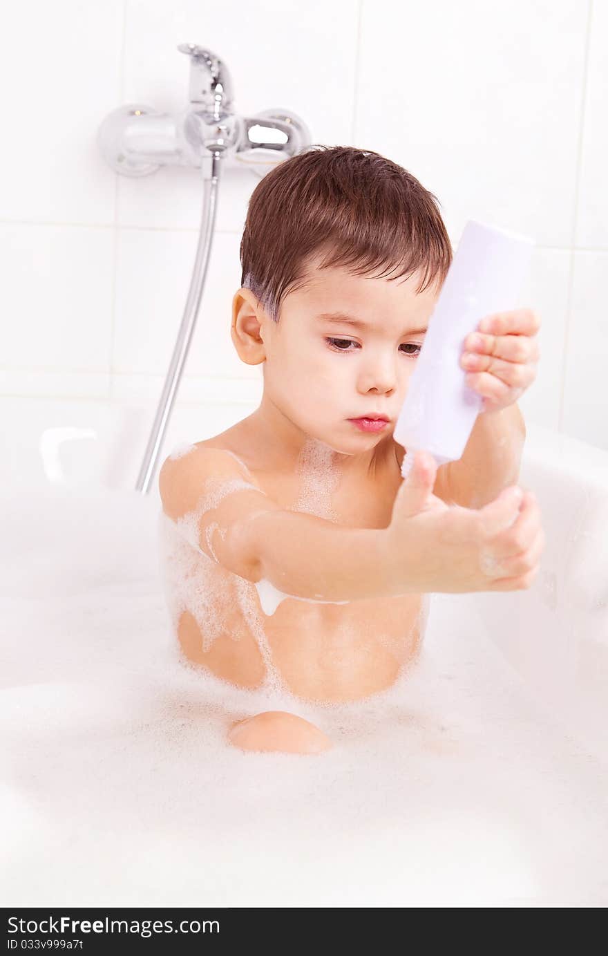 Cute four year old boy taking a relaxing bath with foam and using cosmetics. Cute four year old boy taking a relaxing bath with foam and using cosmetics