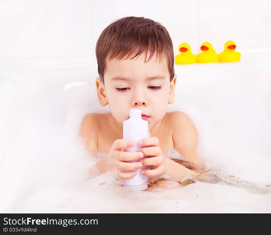 Cute four year old boy taking a relaxing bath with foam and using cosmetics. Cute four year old boy taking a relaxing bath with foam and using cosmetics