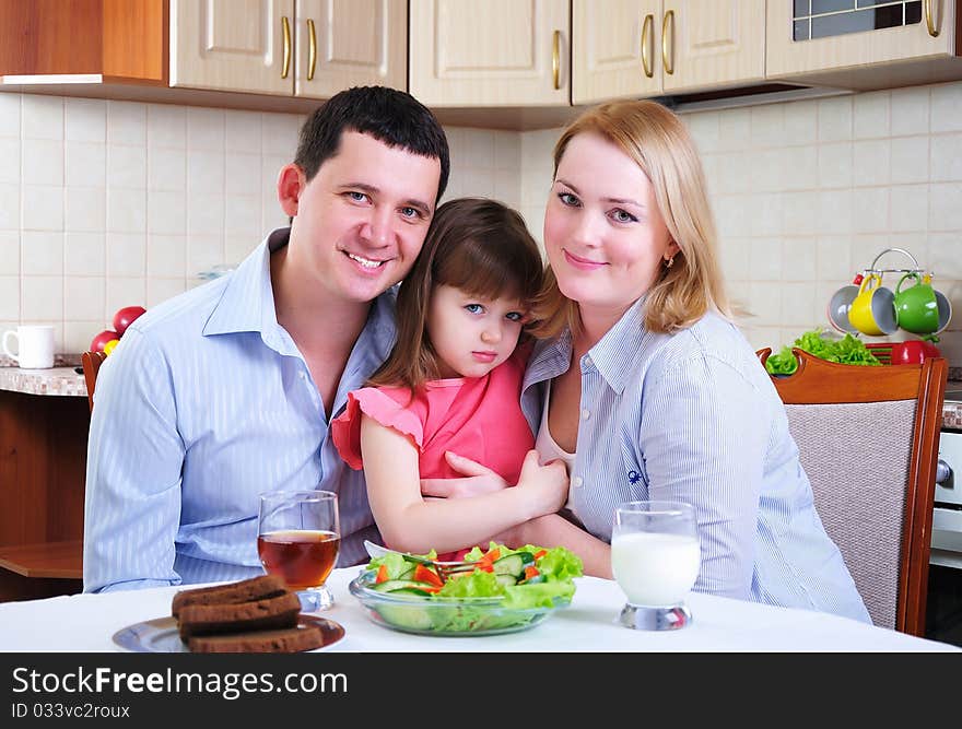 Dad, Mom and their little daughter lunching together in his kitchen.