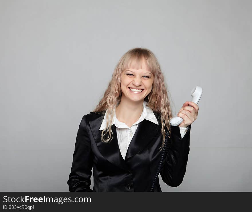 Funny business woman in a black suit with a gray background with the handset in the hands