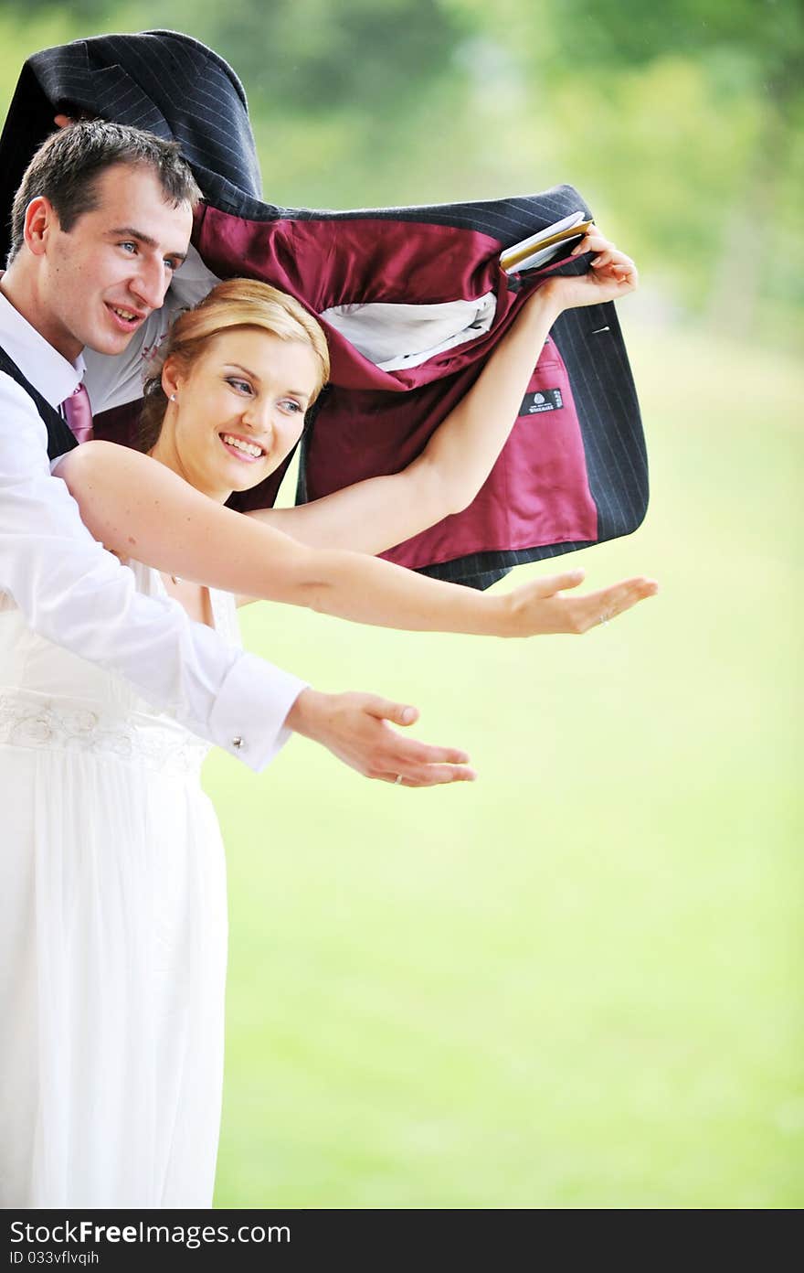 Cheerful young pair in  wedding day hides from  rain. Cheerful young pair in  wedding day hides from  rain