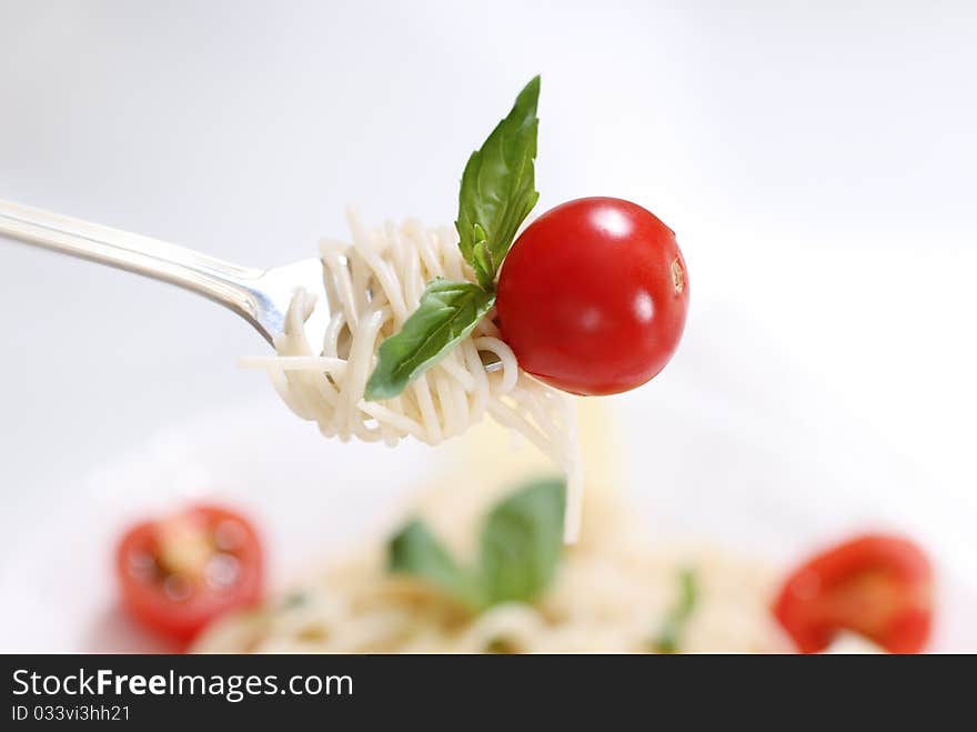 Spaghetti, basil and tomato on fork