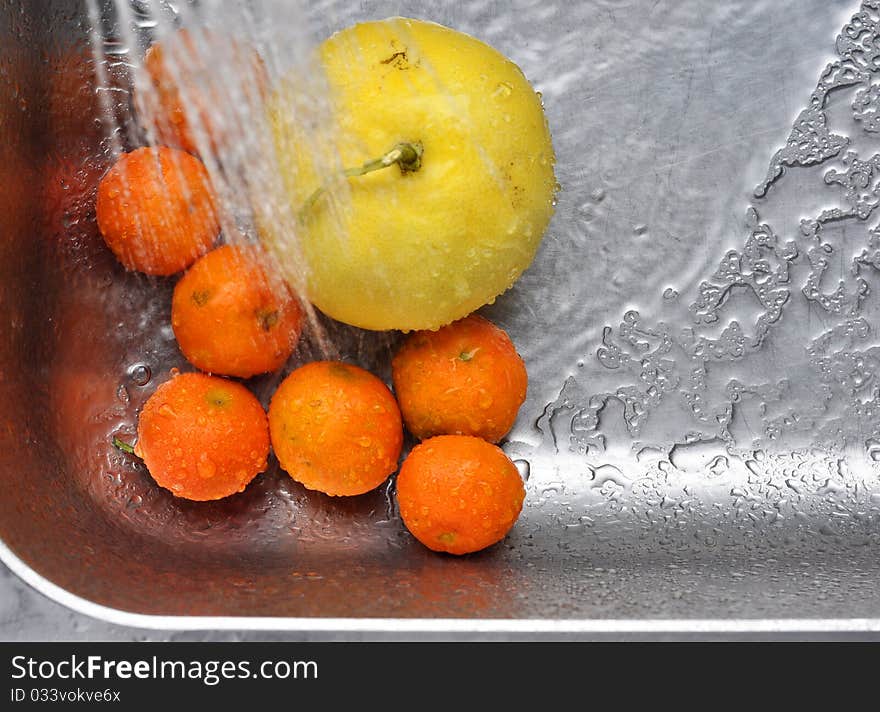 Citrus fruits in a kitchen sink are being washed. Citrus fruits in a kitchen sink are being washed