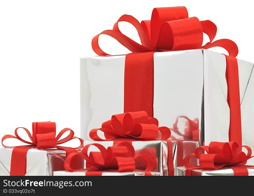 Gifts in silver wrapping with red bow isolated on white background. Gifts in silver wrapping with red bow isolated on white background