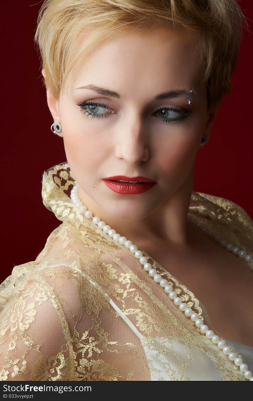 The beautiful girl in a pearl necklace on a red background. The beautiful girl in a pearl necklace on a red background