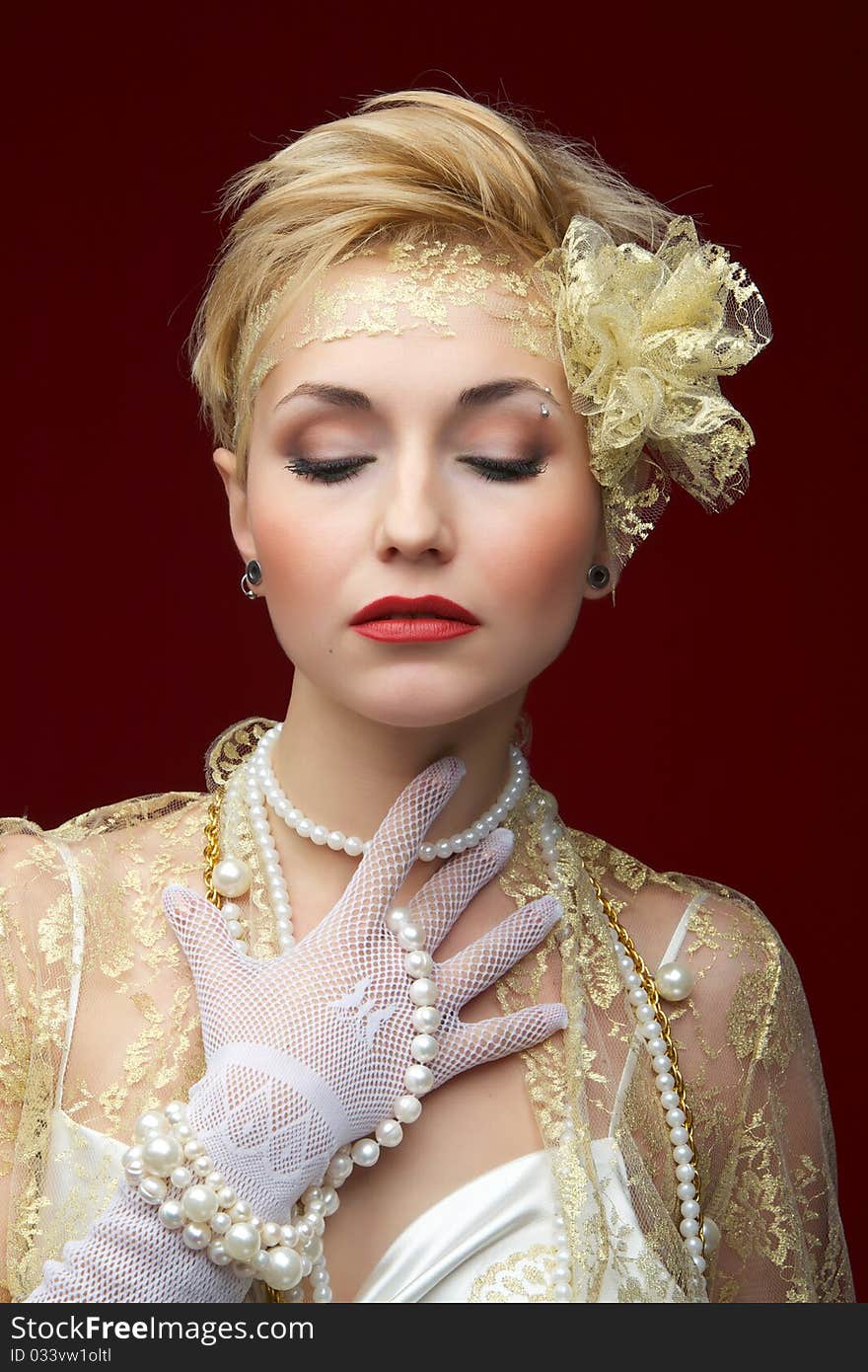 The beautiful girl in a pearl necklace on a red background. The beautiful girl in a pearl necklace on a red background